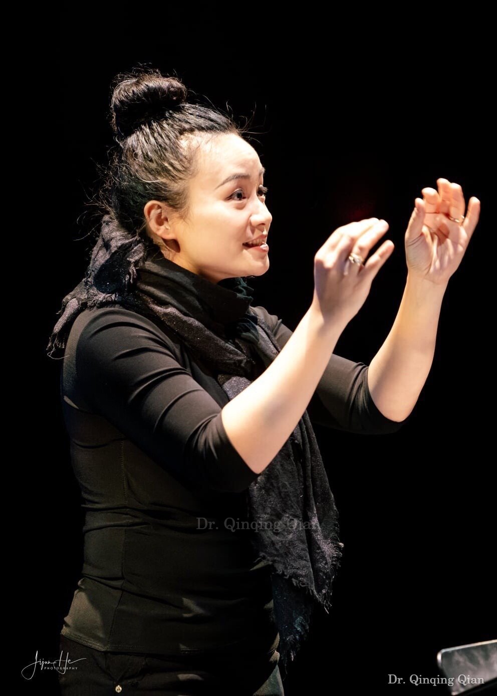 Dr. Qian conducting with an expressive raised hand